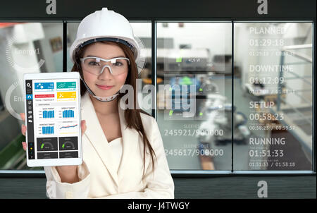 Smile young Asia female Engineer using tablet , wear glasses and tablet in smart factory industrial with real time monitoring production system indust Stock Photo
