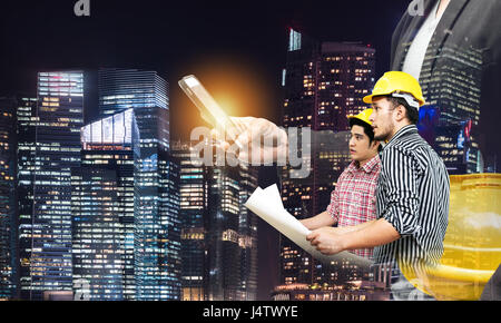Smart construction in industry 4.0 concept. Double exposure of business man hand using mobile phone and two engineers worker with graphic popup,drone, Stock Photo