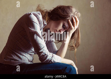 Young sad girl sitting alone in an empty room Stock Photo