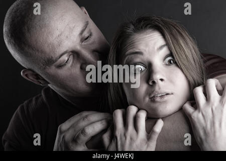 Domestic violence woman being abused and strangled by strong man Stock Photo