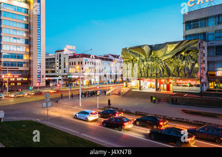 Minsk, Belarus - April 3, 2017: Evening Night Traffic Near Bas-relief of the Soviet era on old facade building On Illuminated Nemiga Street In Minsk,  Stock Photo