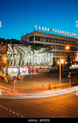 Minsk, Belarus - April 3, 2017: Evening Night Traffic Near Bas-relief of the Soviet era on old facade building On Illuminated Nemiga Street In Minsk,  Stock Photo