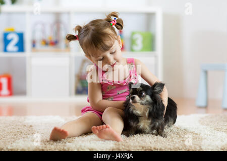 Little girl and small cute dog in the living room Stock Photo