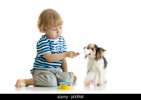 Kid playing with dog and feeding his with toy spoon Stock Photo