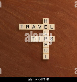 Crossword puzzle with words Helpful Travel Tips. World travel concept. Ivory tiles with capital letters on mahogany board. Stock Photo