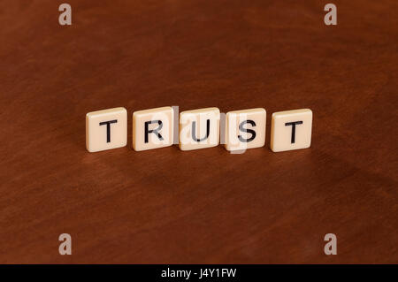 Trust sign. Loyalty concept. Ivory tiles with capital letters on mahogany board. Stock Photo