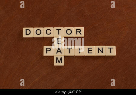 Crossword puzzle with words Doctor, Patient, Team. Healthcare concept. Ivory tiles with capital letters on mahogany board. Stock Photo
