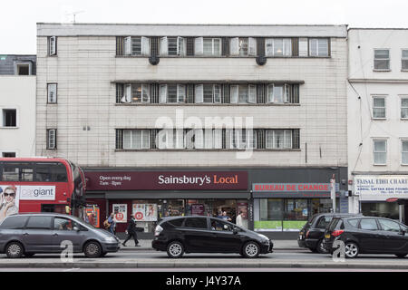 London, England - July 15, 2016: Traffic queuing on the Edgware Road beside run-down buildings and a Sainsbury's Local supermarket near Paddington in  Stock Photo