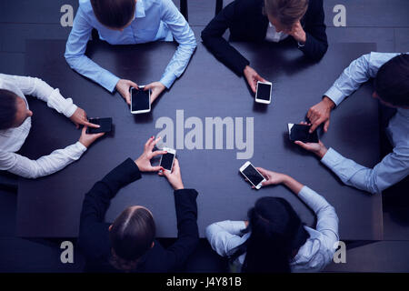 Business people with smartphones sitting around the table, top view Stock Photo