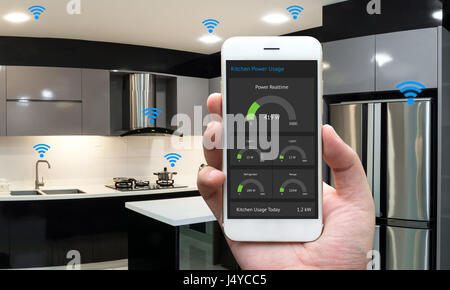 Internet of things , iot , smart home , kitchen , network connect concept. Human hand holding white phone, smart home application to count power usage Stock Photo