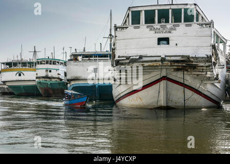 Stern view of pinisi with a small wooden canoe, Sunda Kelapa Harbour, Jakarta, Indonesia Stock Photo