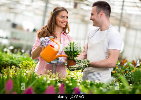 Young workers water flowers in hothouse Stock Photo