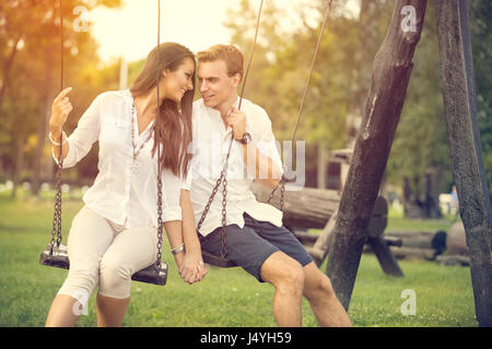 Amorous couple on romantic date on swings outdoor Stock Photo