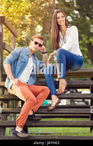 young fashion couple sitting together and relaxing in park Stock Photo