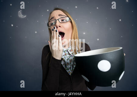 tired female student yawning with big cup of coffee Stock Photo