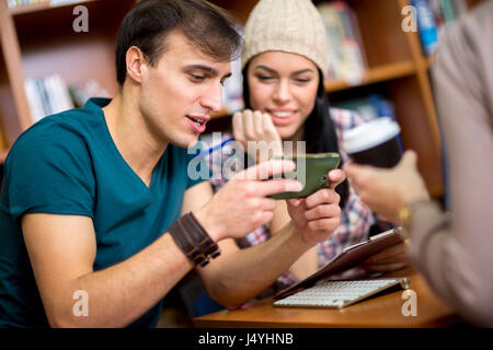 Students looking in funny message on mobile phone and having fun Stock Photo