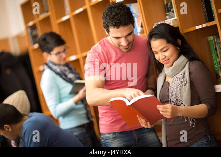 Couple of studying  friends reading book from library Stock Photo