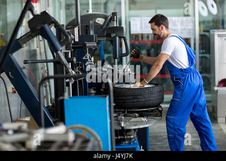 repairman balancing  car wheel on balancer in workshop Stock Photo