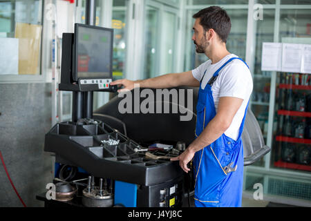 Mechanic working on balancing machine at the garage Stock Photo