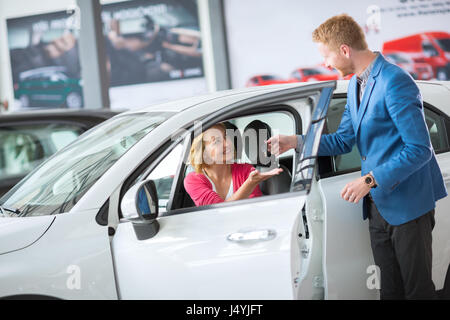 Sales manager giving key from the new car female client Stock Photo