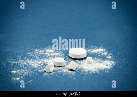 Still life of pills and its powder on blue background Stock Photo