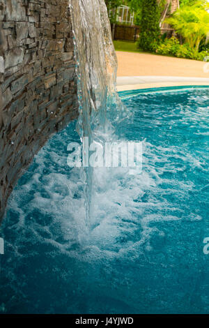 Small artificial waterfall in the swimming pool Stock Photo