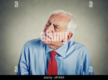 Closeup portrait headshot senior man hard of hearing asking someone to speak up can't hear isolated gray wall background. Stock Photo