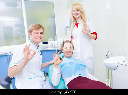 Group portrait happy health care professionals dentist assistant satisfied smiling female patient in medical office giving ok sign. Clinical patient p Stock Photo