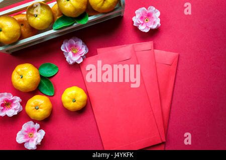 Top view accessories Chinese new year festival decorations.orange,leaf,wood basket,red packet,plum blossom on red background. Stock Photo