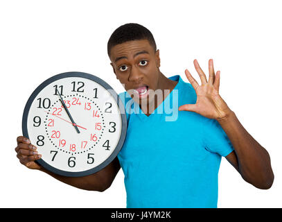 Closeup portrait funny looking man student holding wall clock, stressed biting fingernails pressured by lack, running out of time, late meeting, inter Stock Photo