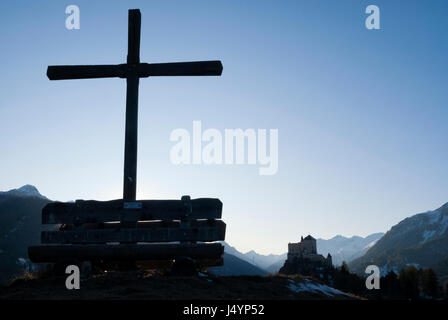 Wooden cross on a hill with Tarasp castle in the background in the swiss canton Graubunden Stock Photo