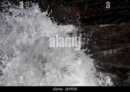 Breaking Wave Against Rocks Stock Photo