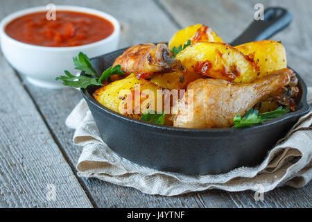 Baked potatoes with chicken in a cast-iron frying pan. Stock Photo