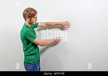 Young Adult Male Presenter in Green T-Shirt Gesturing, Showing, Teaching Stock Photo