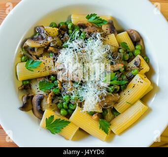 Rigatoni pasta with mushrooms, green peas, butter, and Parmigiano Reggiano cheese Stock Photo