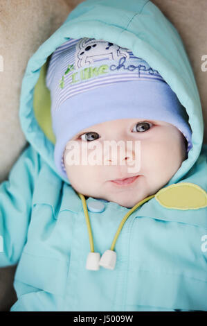 baby in blue jacket smiling at the camera Stock Photo