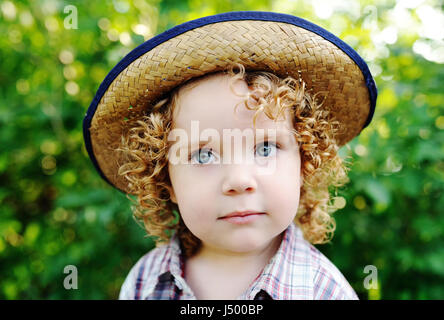 portrait of curly red-haired baby in a hat. Stock Photo