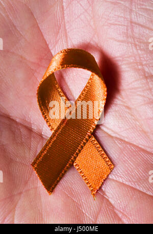 closeup of an orange ribbon placed on the palm of the hand Stock Photo