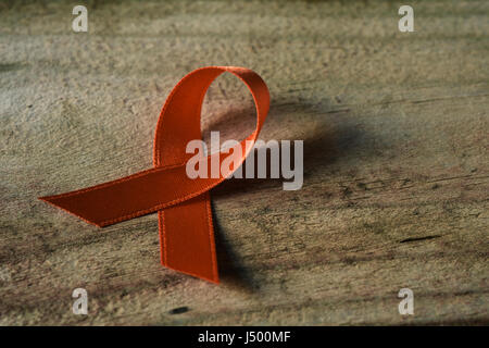 Top view of orange ribbon on dark wood background. Leukemia