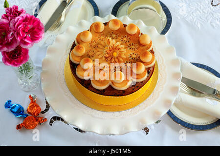 Simnel cake - traditional Easter fruit cake decorated with marzipan on a table set for tea. Stock Photo