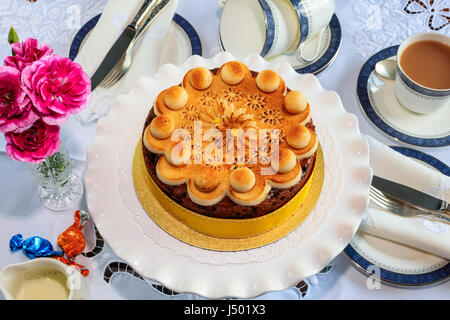 Simnel cake - traditional Easter fruit cake decorated with marzipan on a table set for tea. Stock Photo