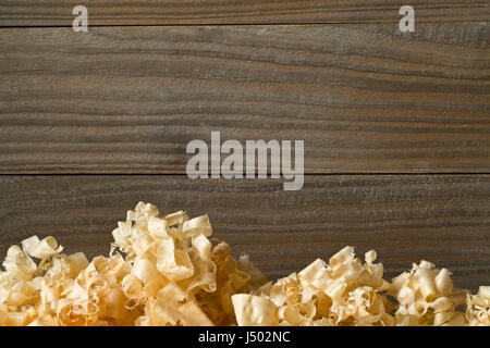 Light brown wood shavings from carpenter's hand planer or chisel work on wooden boards background with copy space Stock Photo