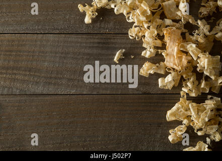 Light brown wood shavings from carpenter's hand planer or chisel work on wooden boards background with copy space Stock Photo