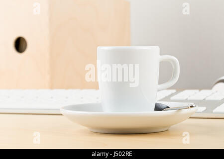Office desk with cup, folders and laptop with empty screen copy space - workplace or coffee break concept Stock Photo