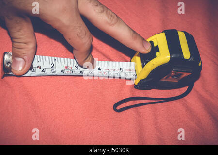 man measuring with tape measure on red background Stock Photo