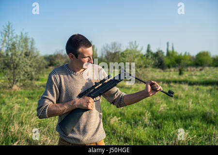 The man recharges sniper rifle outdoor. Selective Focus Stock Photo