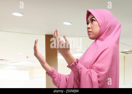 Religious asian muslim woman with hijab praying to god in the mosque Stock Photo