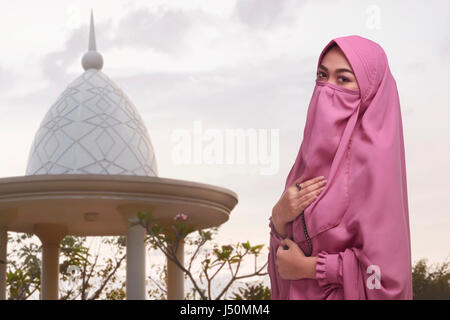 Religious asian muslim woman with traditional dress holding prayer beads in the mosque Stock Photo