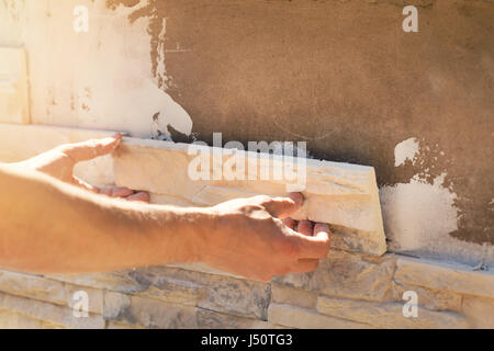 worker installing decorative stone tiles on house facade Stock Photo