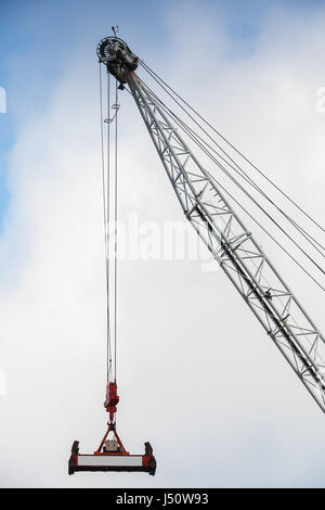 Steel crane boom with container spreader hanging on ropes Stock Photo